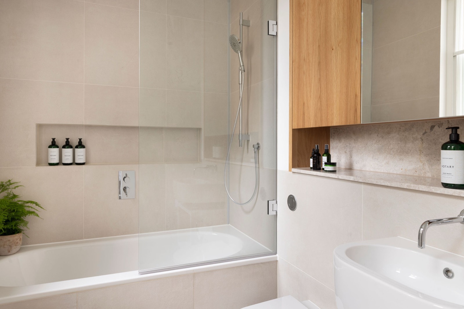 Bath with shower behind a glass screen
