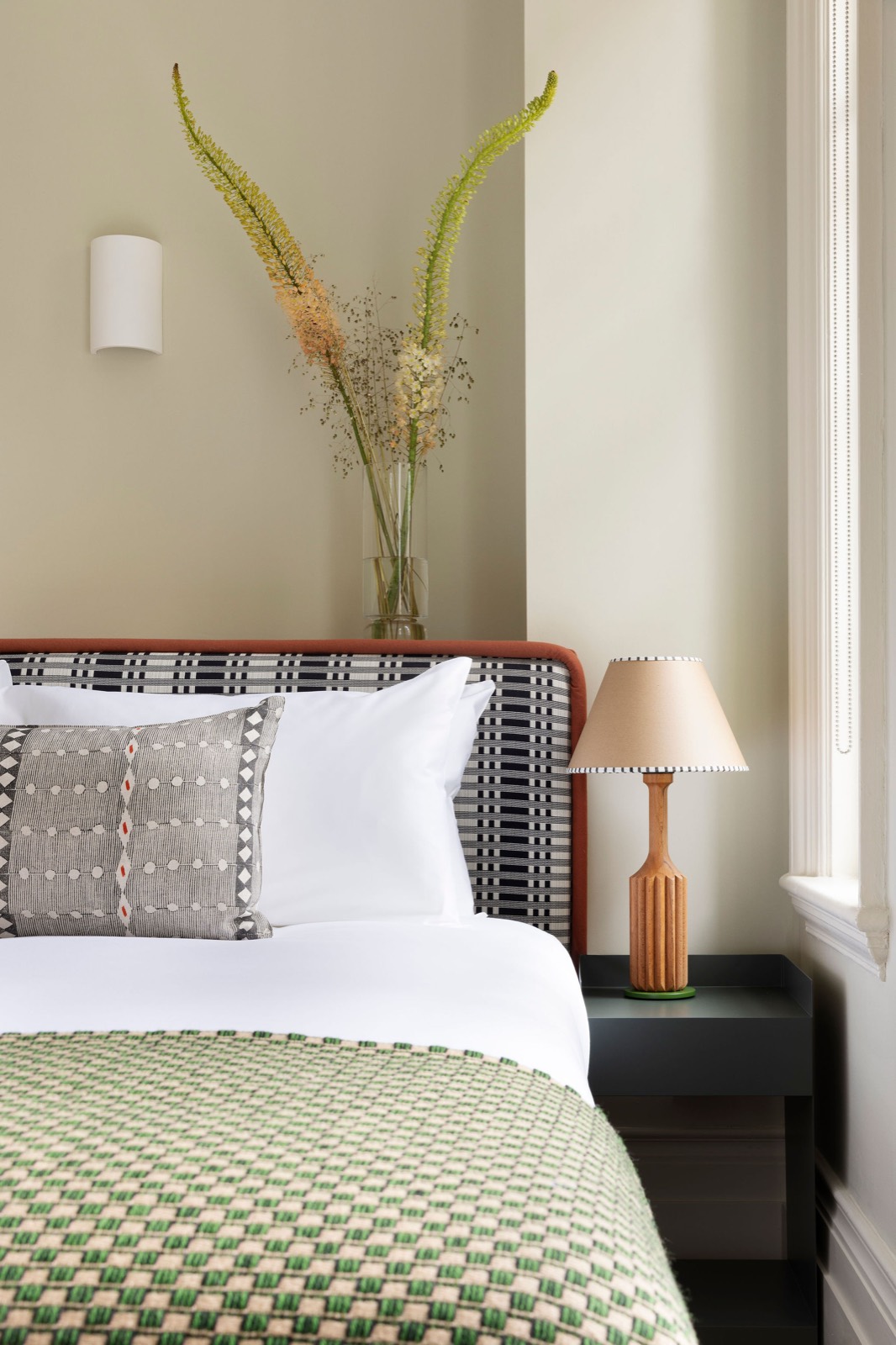 Bedroom with upholstered headboard and woven throw
