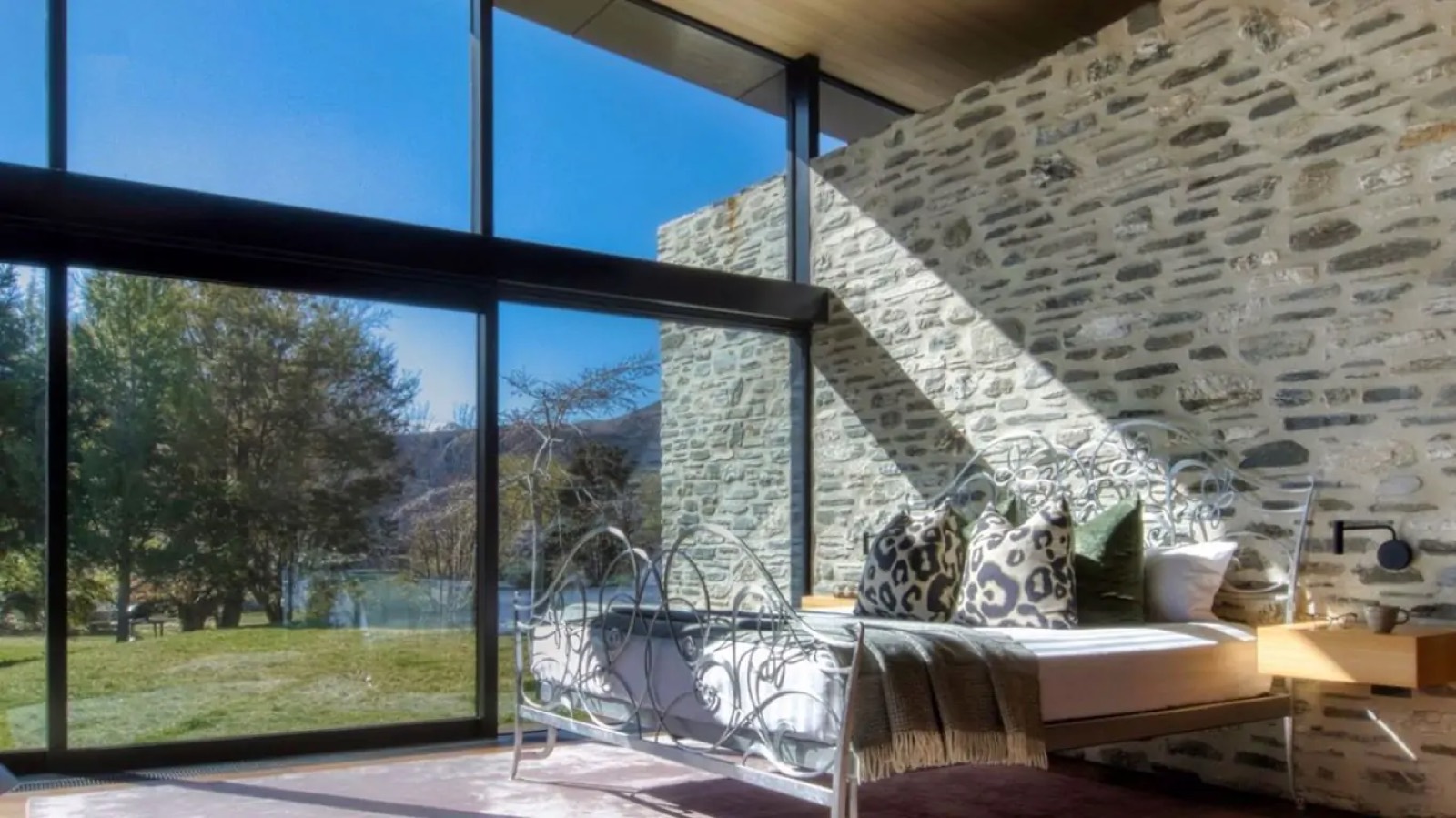 Bedroom with sculpted iron bed and stone wall