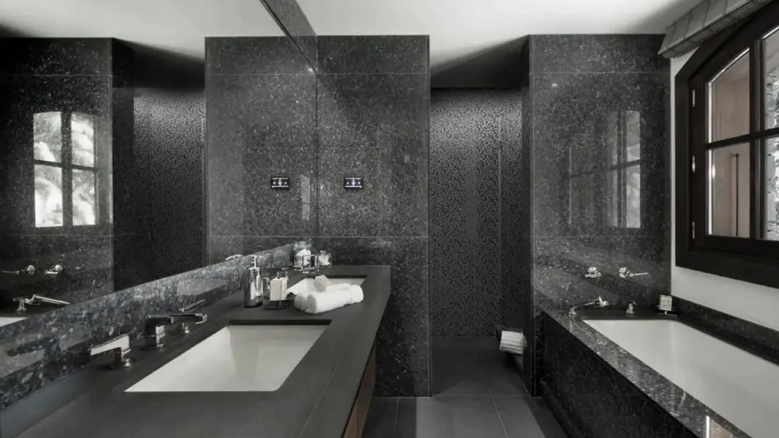 Dark stone bathroom with twin basins and shower