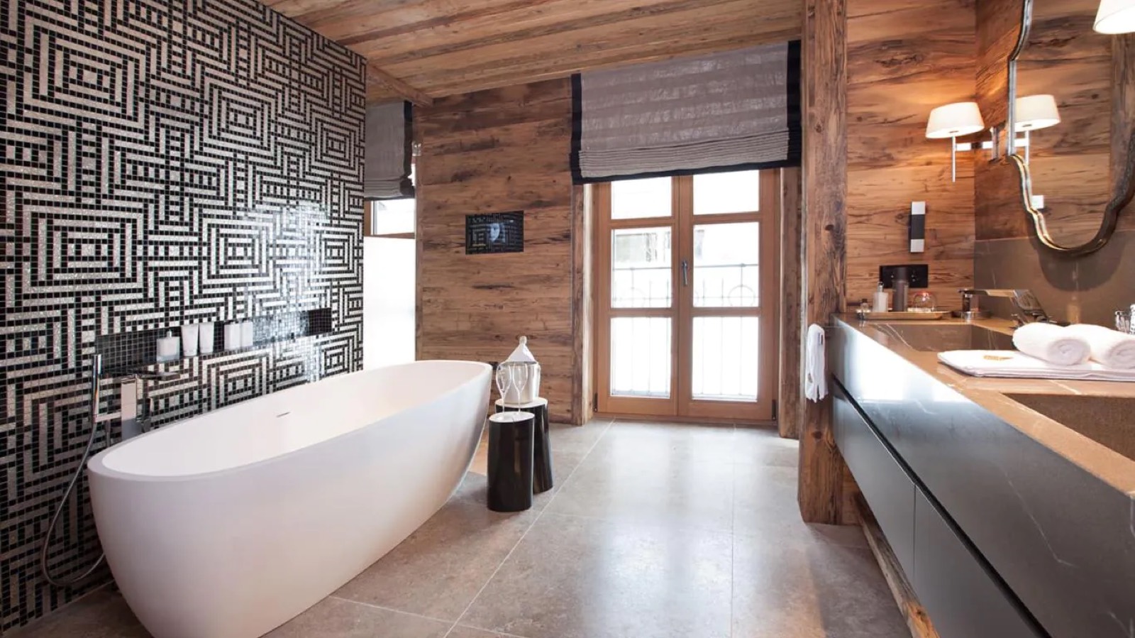 Freestanding bath against a black and white mosaic wall