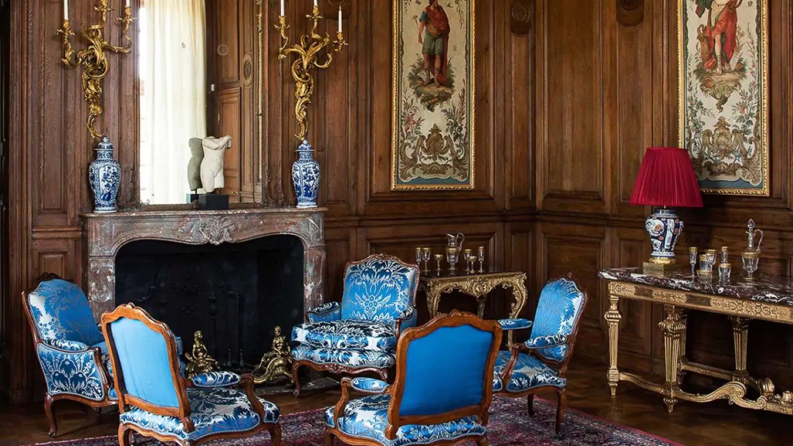 Panelled salon with marble fireplace and blue silk chairs