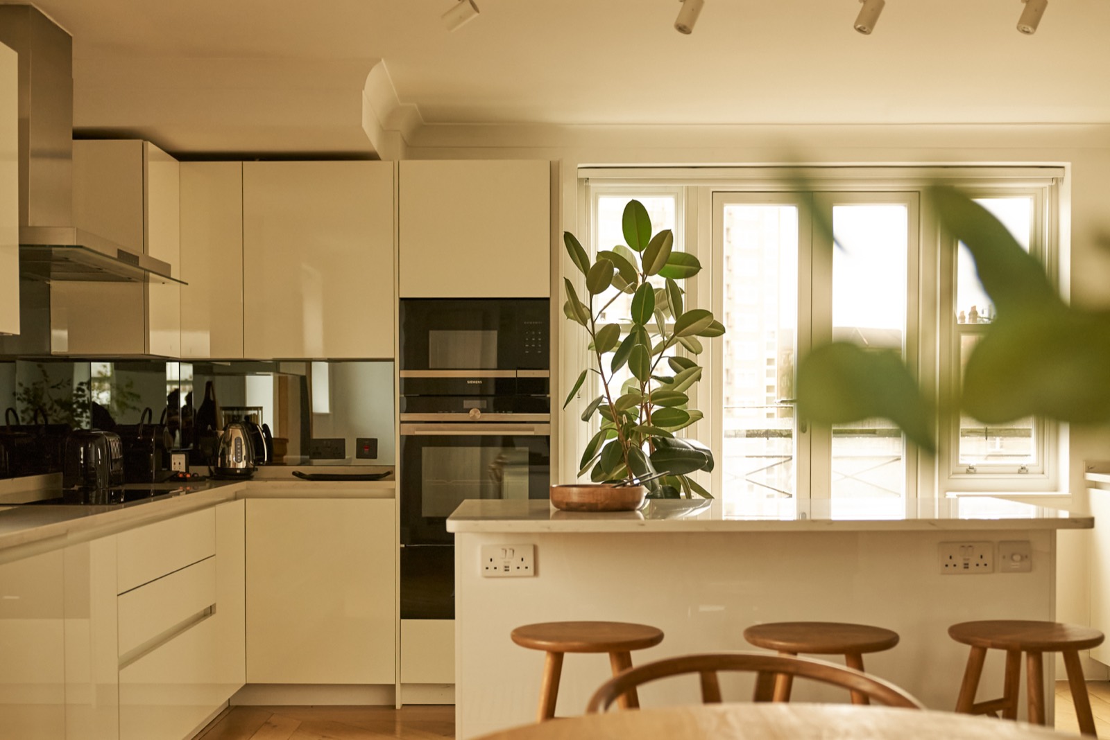 Kitchen with mirrored splashback and integrated ovens