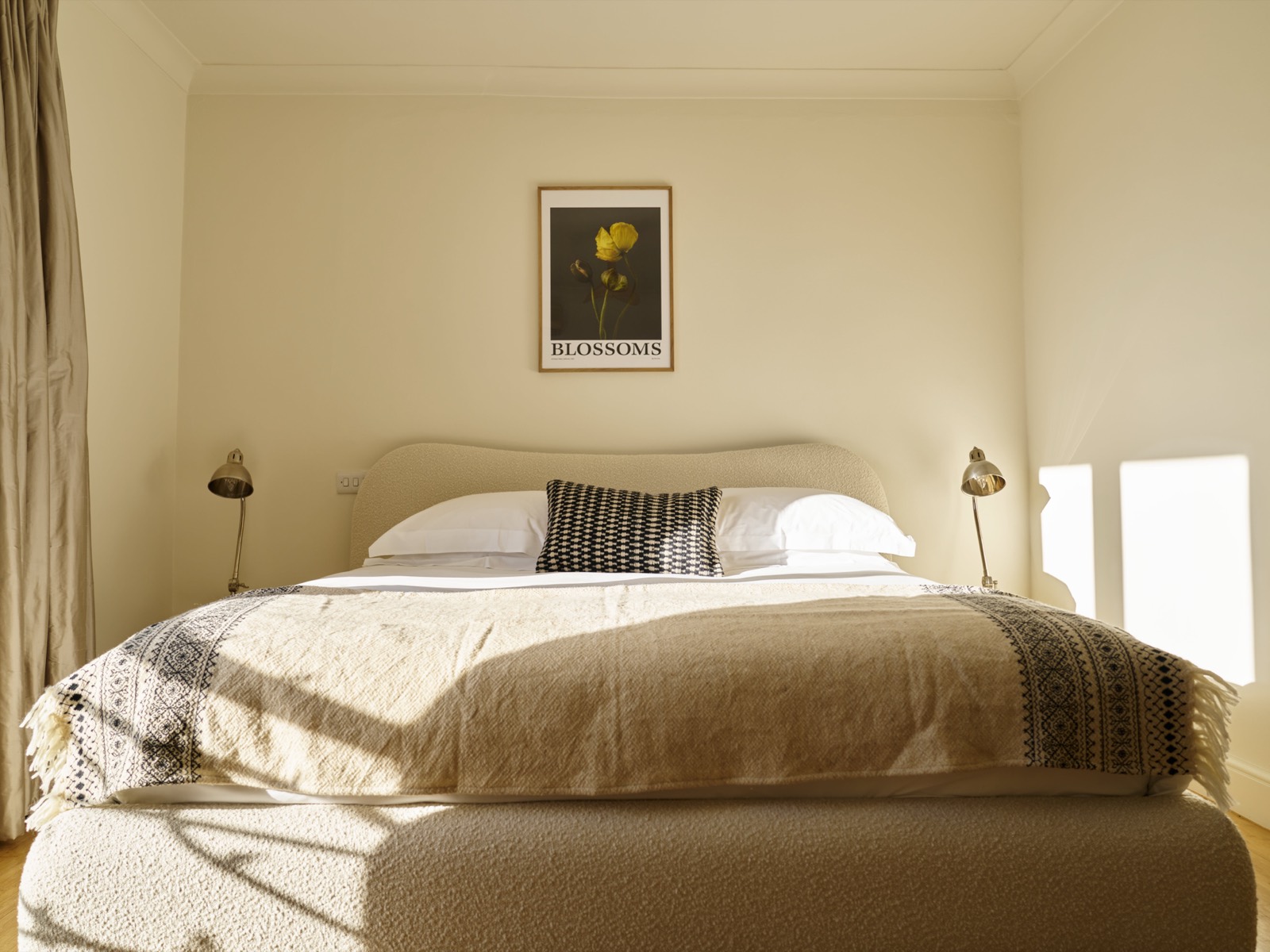 Bedroom with curved headboard and brass lamps
