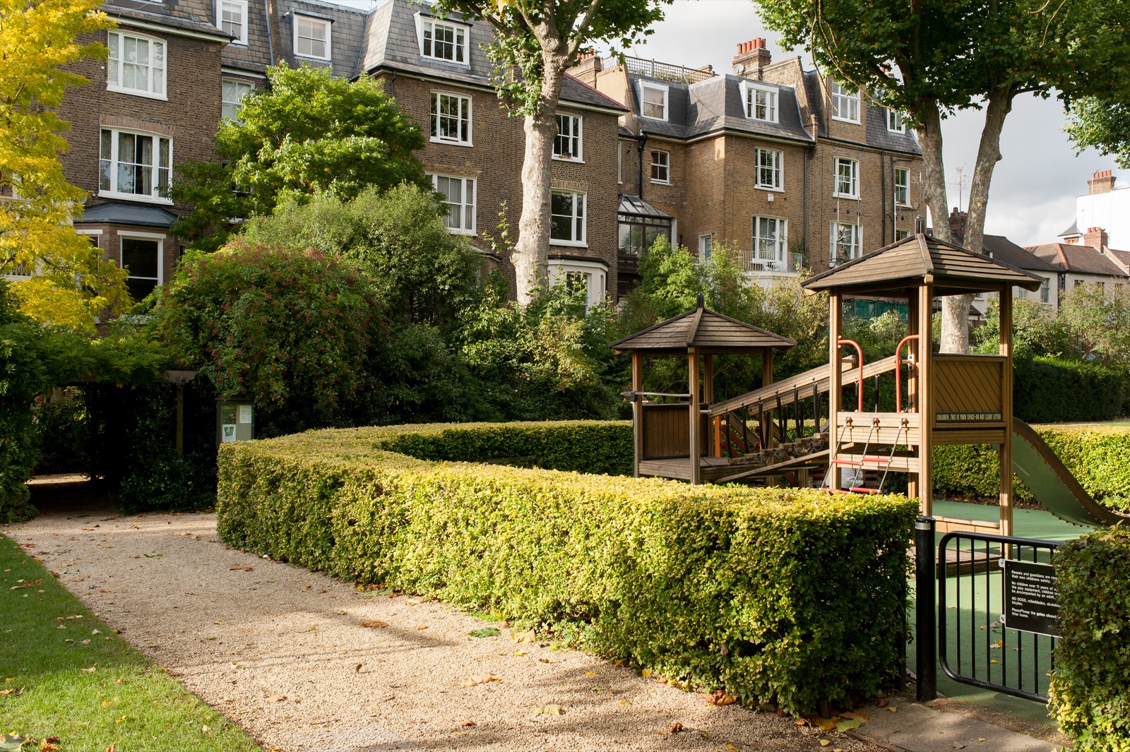 Clipped hedges and playground beside the gravel path