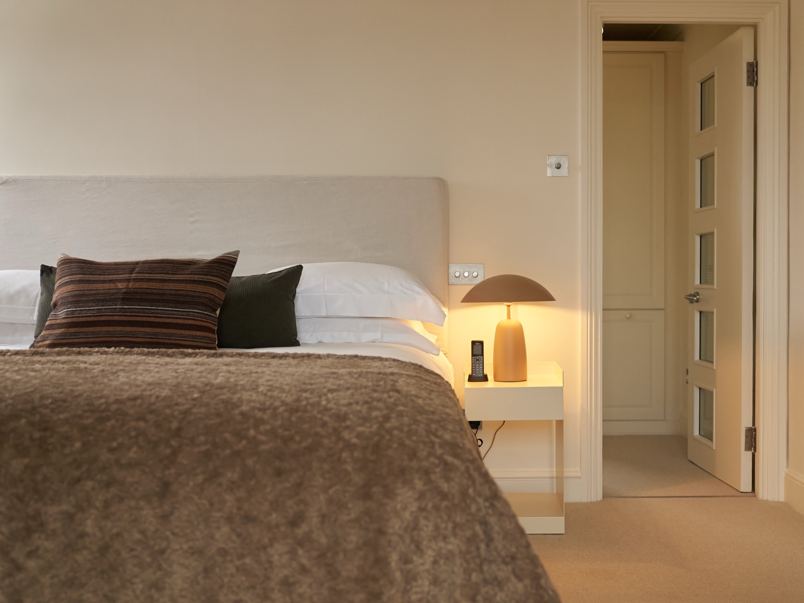 Bedroom with linen headboard and bedside lamp