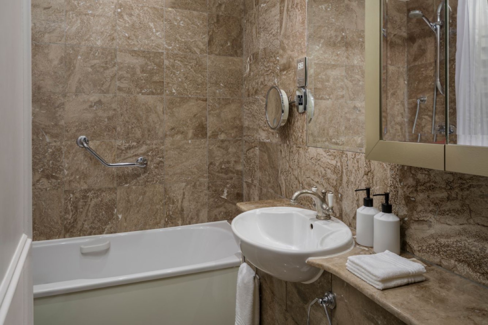 Marble-tiled bathroom with bath and basin