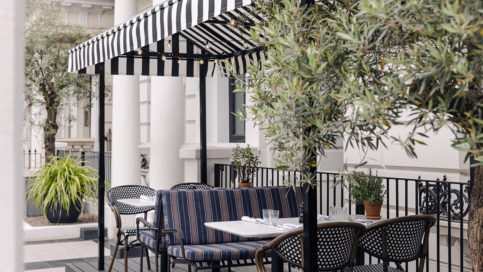Terrace tables beneath the striped awning