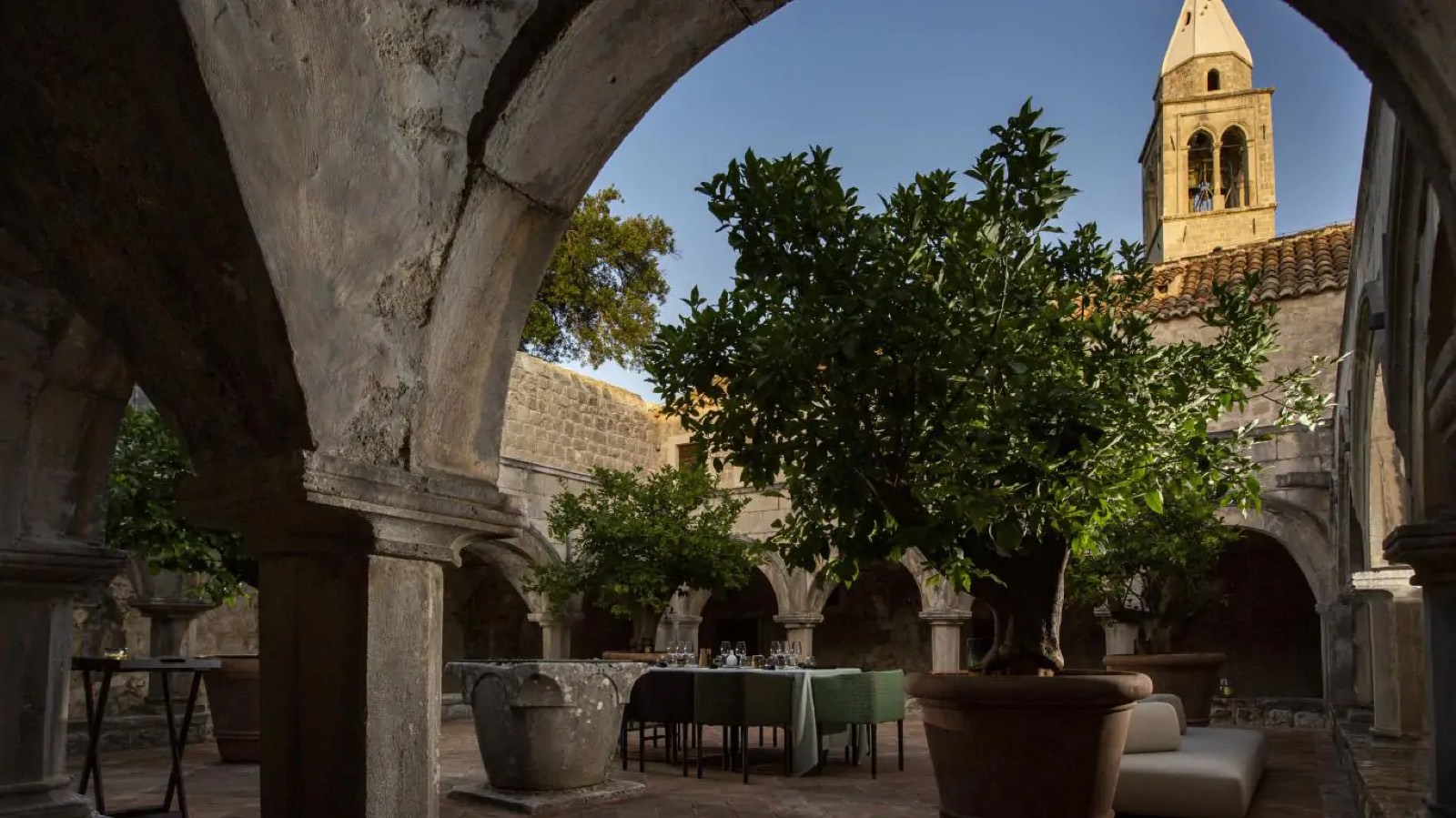 Cloister courtyard laid for lunch beneath citrus trees