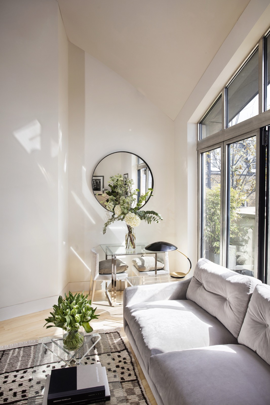 Round mirror and console beside the window