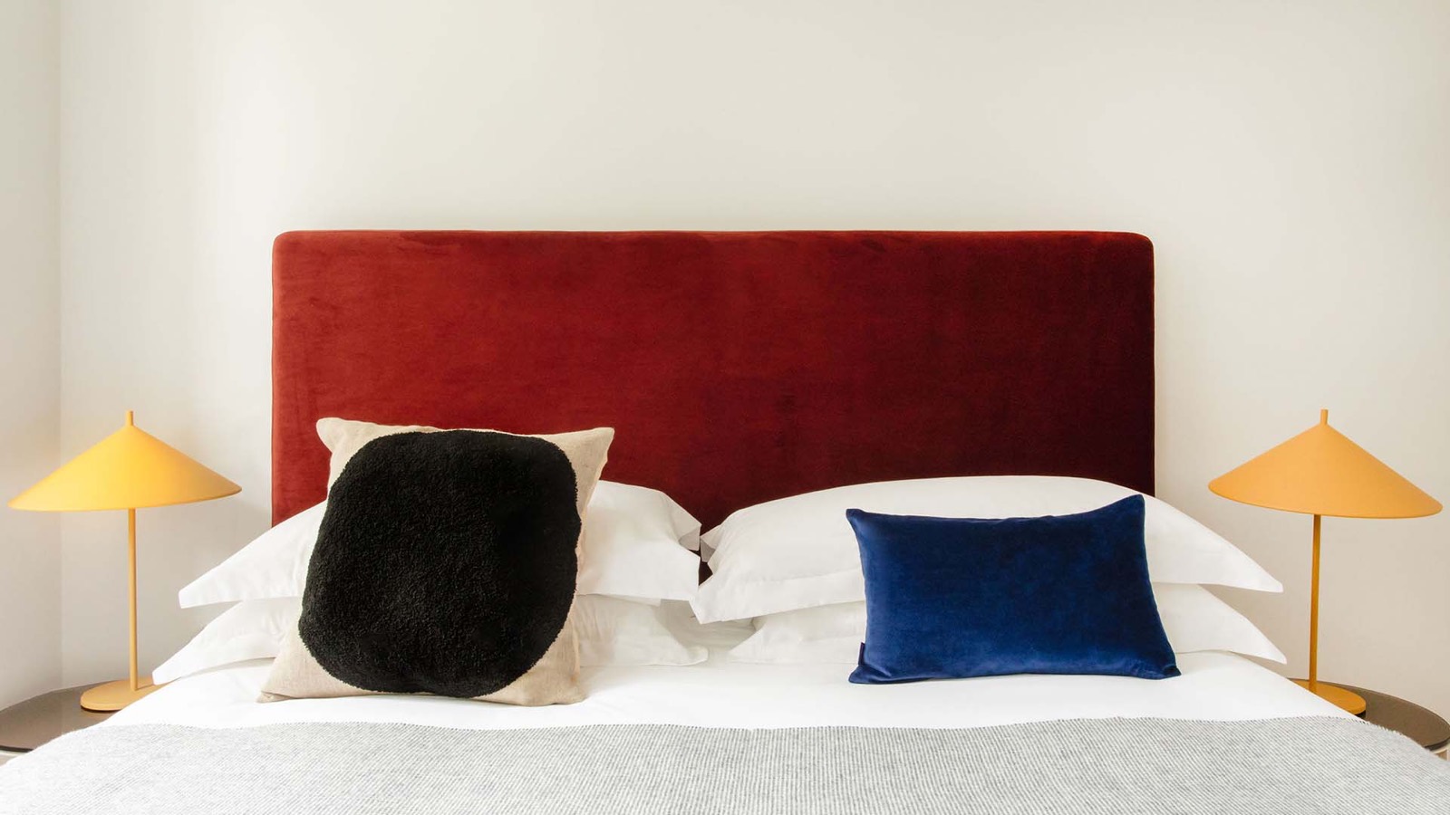 Red velvet headboard flanked by amber lamps