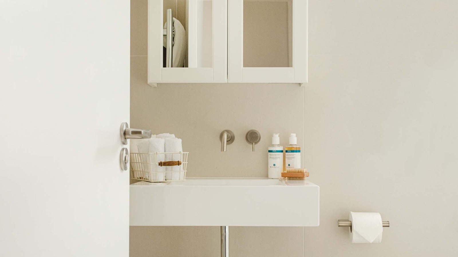 Basin below the mirrored cabinet