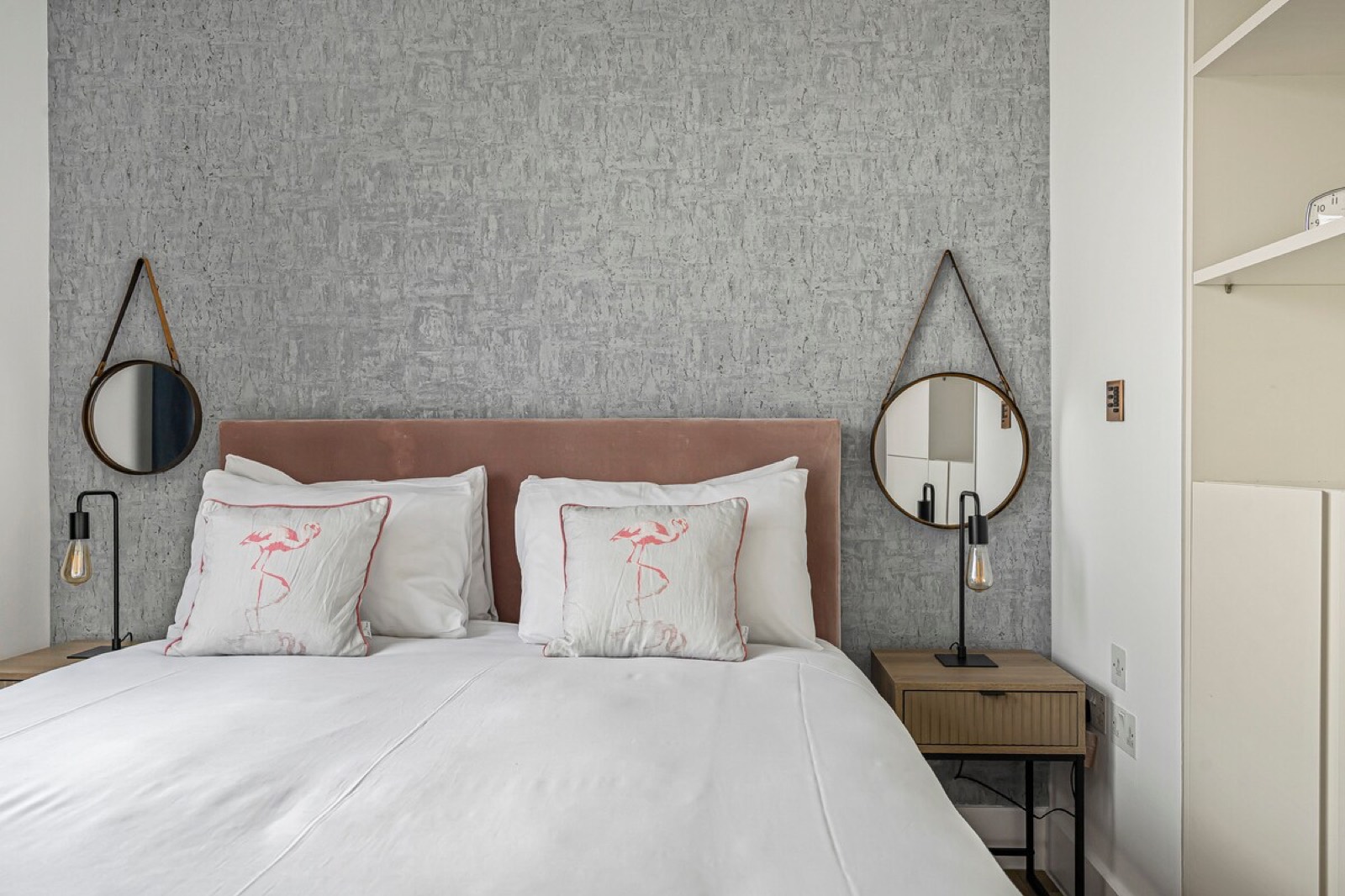 Velvet headboard between two hanging mirrors