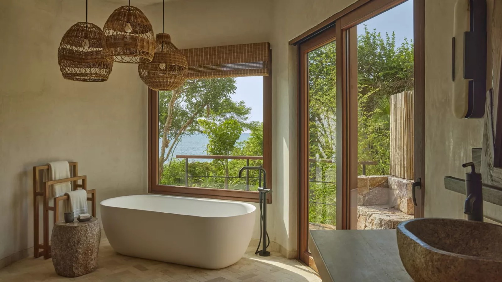 Freestanding bath beneath the window, sea beyond