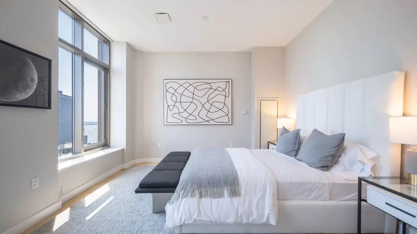 Bedroom with tall upholstered headboard and corner window