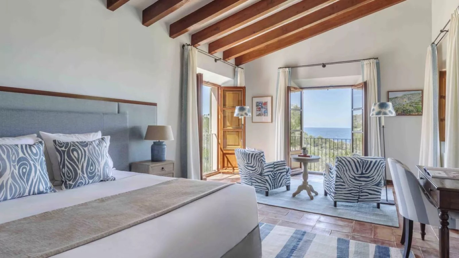 Blue bedroom with armchairs facing the sea