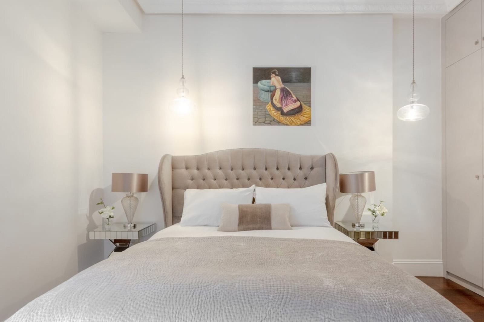 Buttoned headboard framed by hanging glass globes