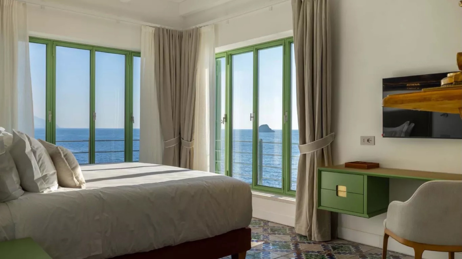 Bedroom with green-framed doors onto the sea