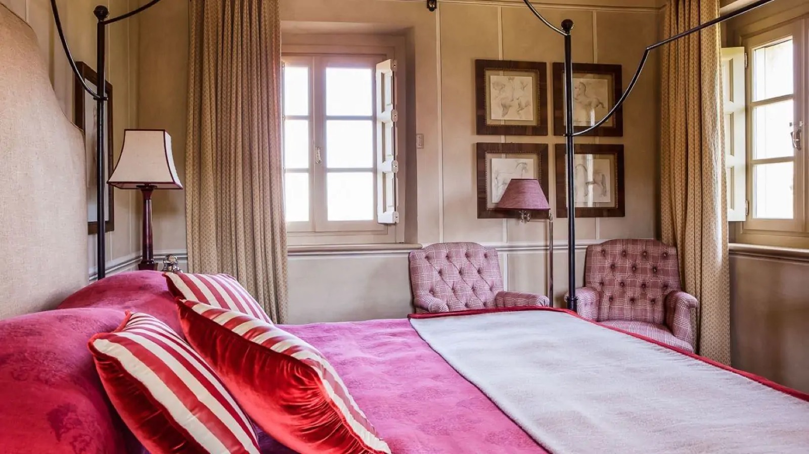 Four-poster bedroom with shuttered windows and armchairs