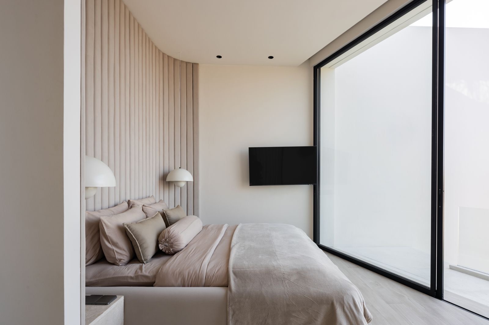 Bedroom with fluted headboard and full-height glass