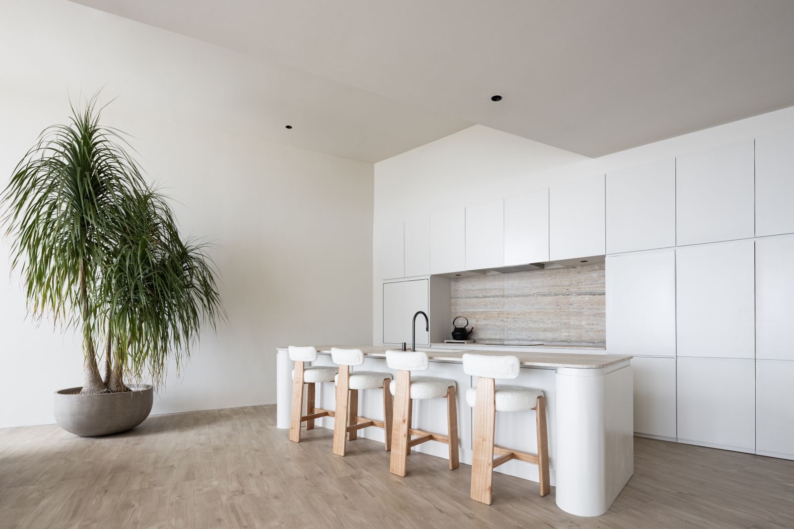 Kitchen island with stools and travertine splashback