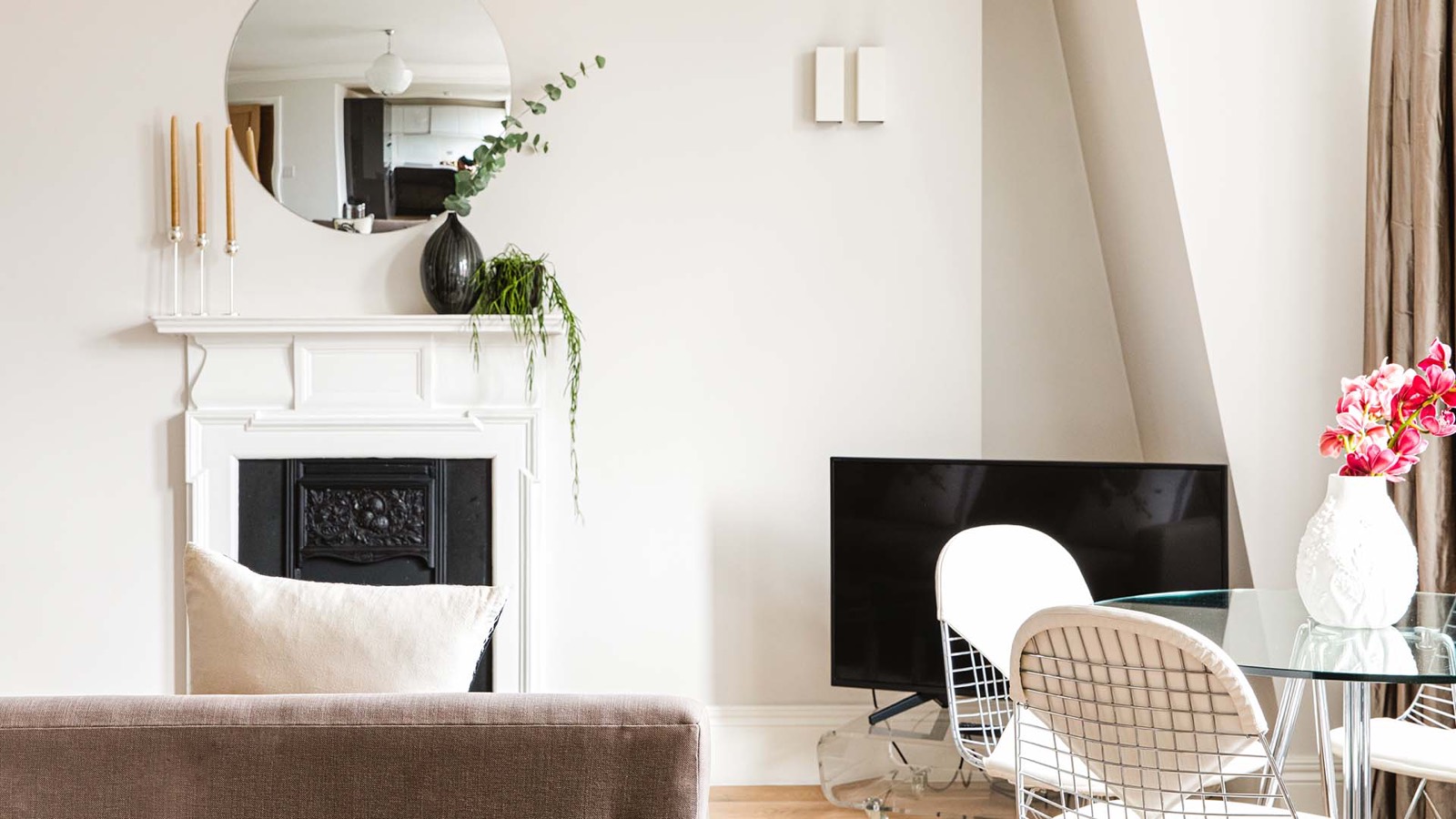Round mirror above the white mantelpiece