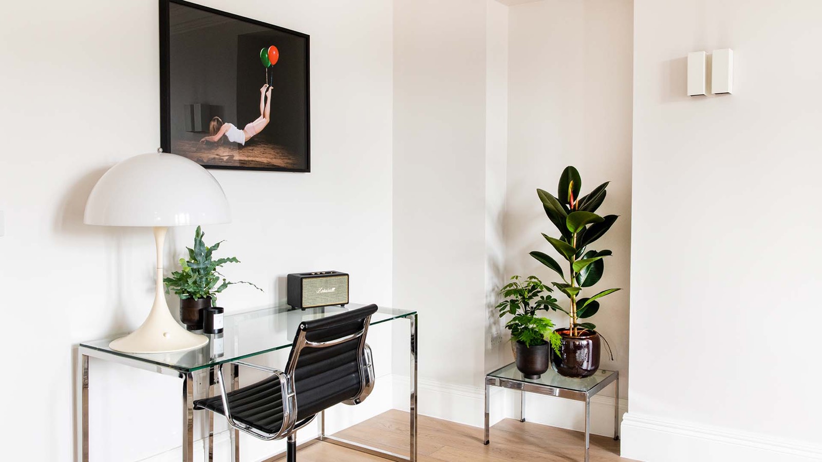 Glass writing desk below a framed print