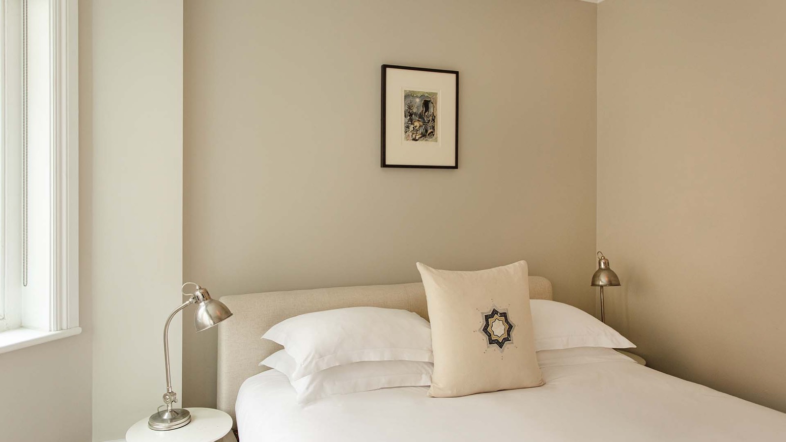 Bedroom with linen headboard and framed print