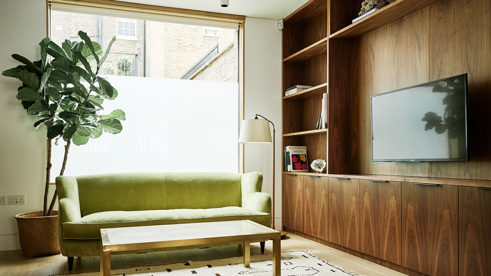 Sitting area with green sofa and walnut joinery