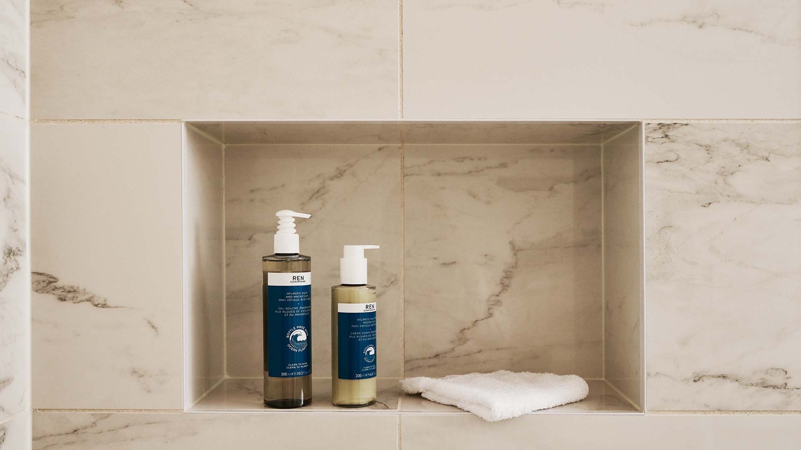 Marble-tiled shower niche with toiletries