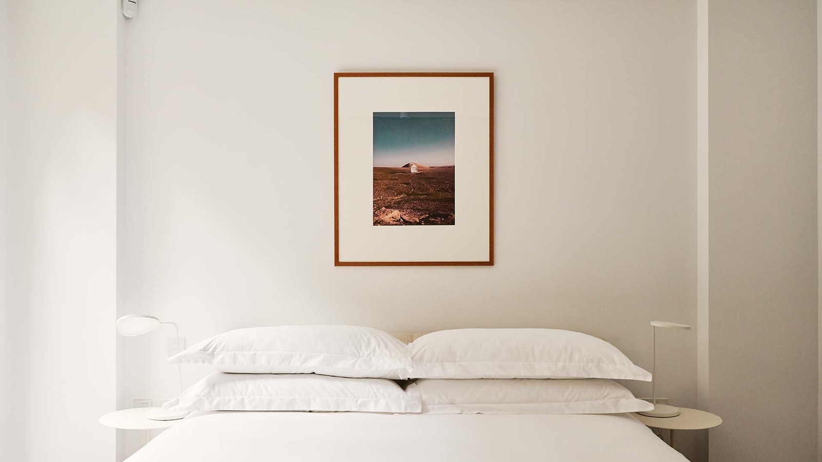 Super-king bed beneath a framed desert photograph