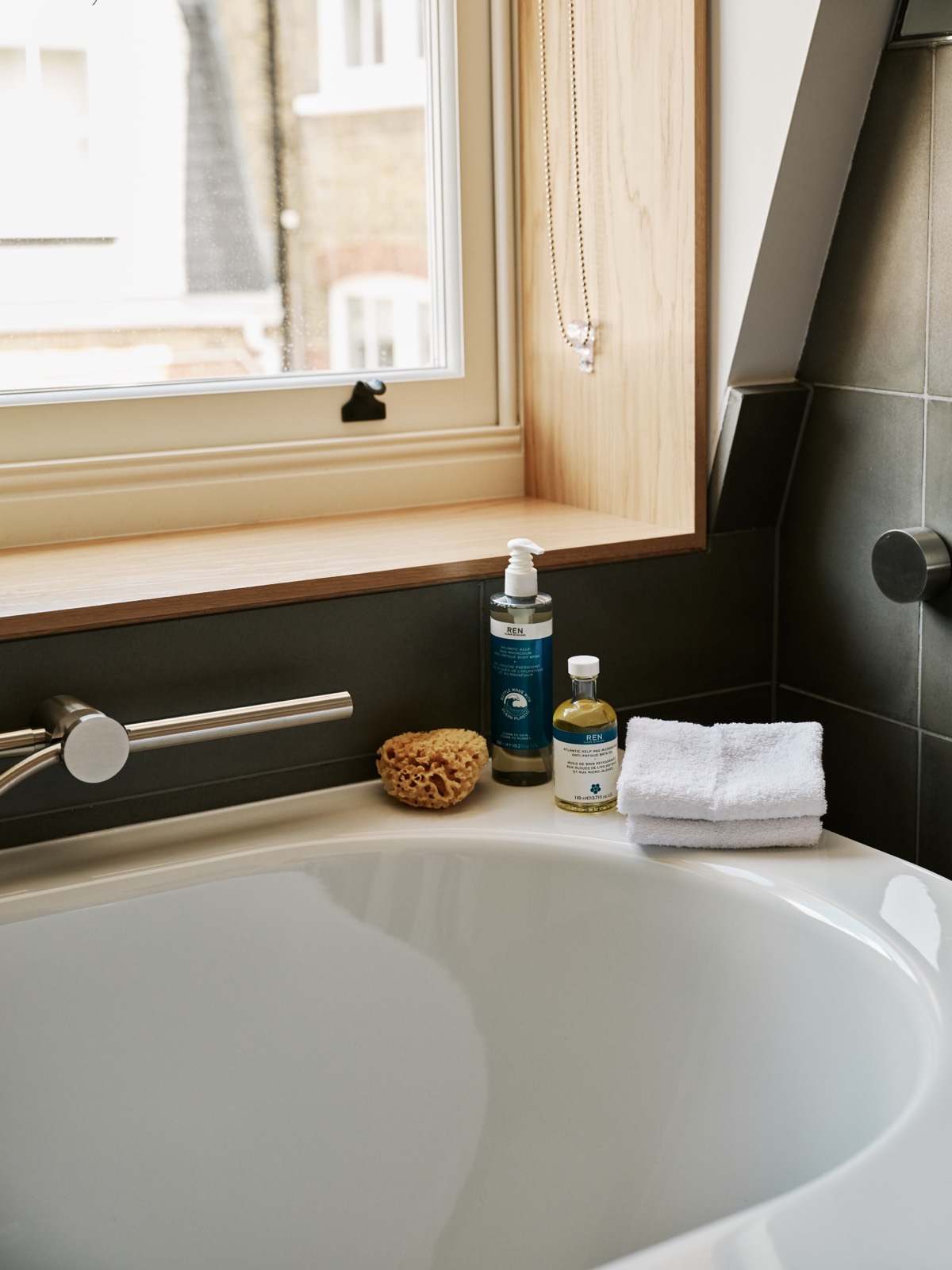 Bath oils and folded towels by the window