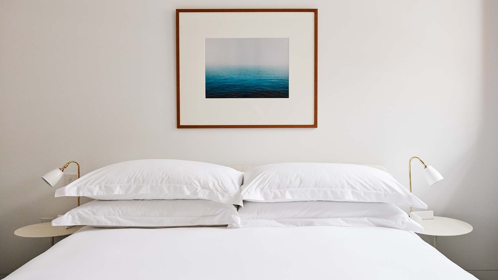 Bedroom with seascape print and brass lamps
